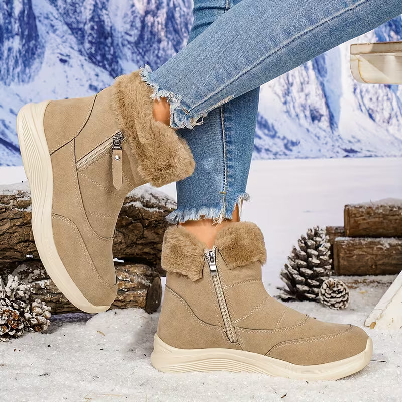 Beige winter boots with fur trim worn by a person in a snowy landscape.