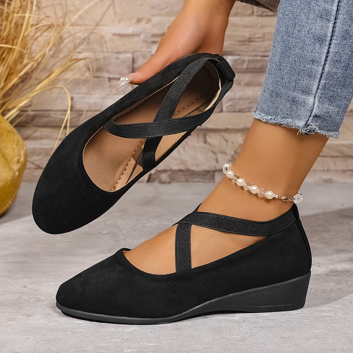 Black wedge sandals worn with jeans on a wooden floor inside view