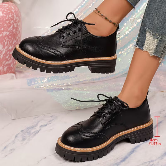 A pair of women's black leather oxford-style shoes with brogue detailing, black laces, and chunky lug soles, shown being worn. One shoe is on a foot with a beaded ankle bracelet, and the other is shown from the side with a red height measurement overlay on a marble floor and sparkly backdrop.