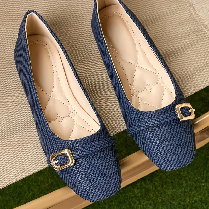 Pair of blue shoes with gold buckles on a textured surface