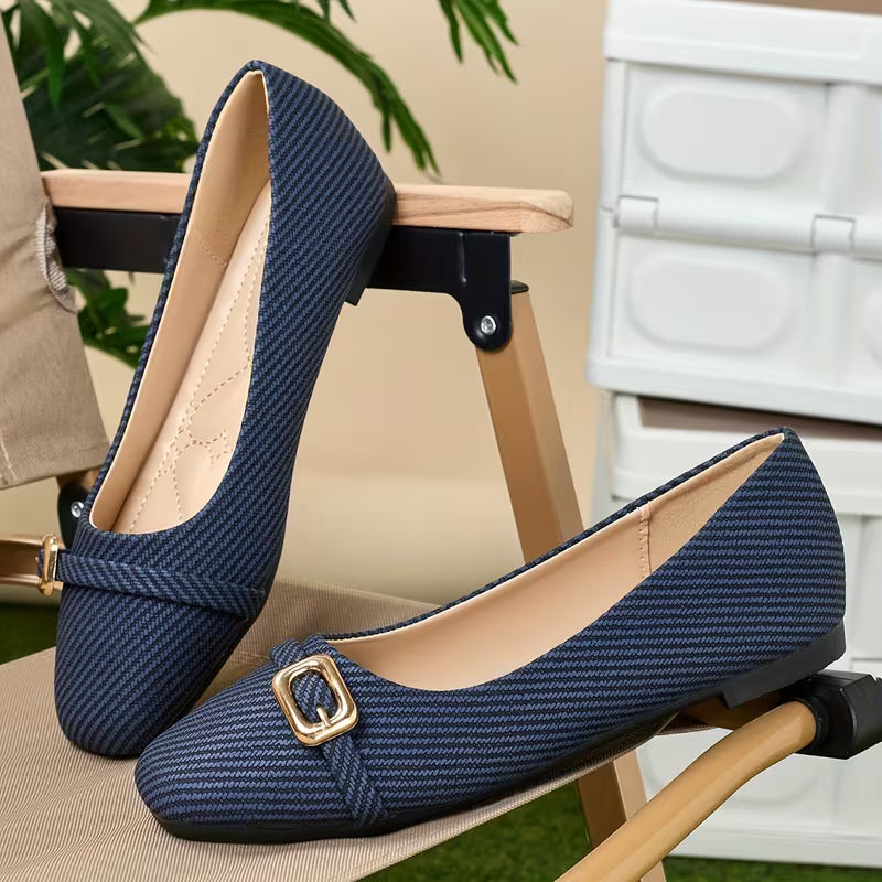 Pair of blue shoes with a gold buckle on a chair