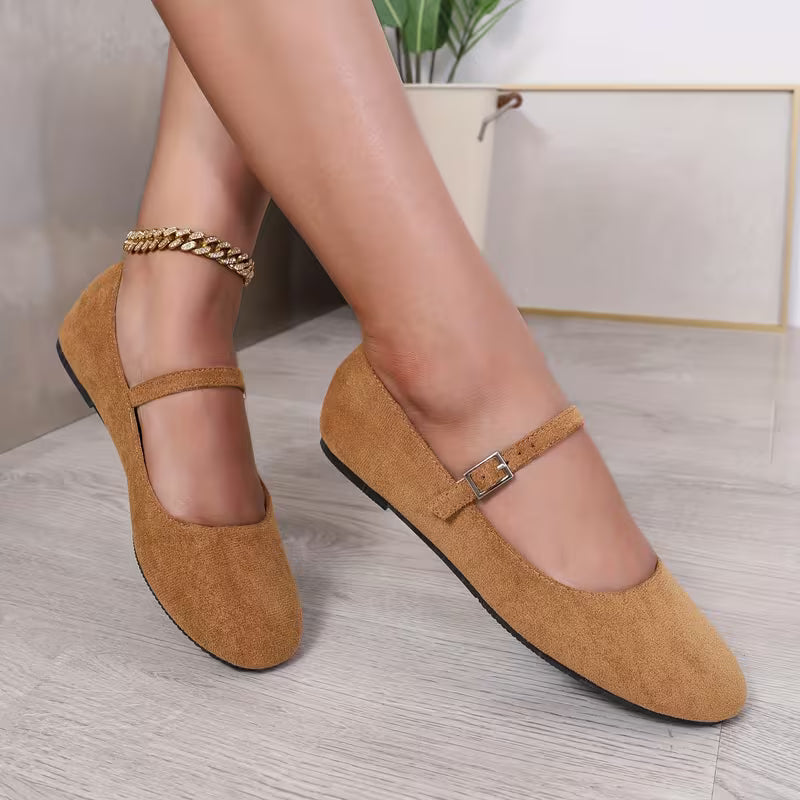 Brown shoes with straps worn by a person on a light wooden floor.