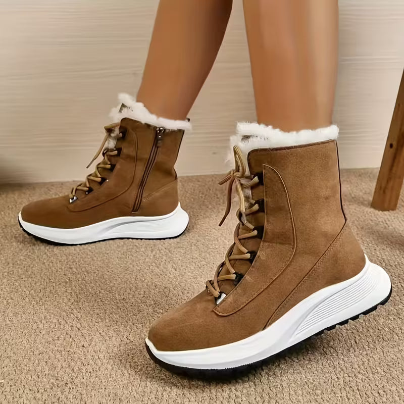 Brown winter boots with white soles and fur lining worn indoors on a carpeted floor.