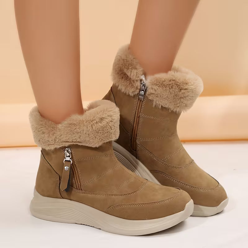 Tan winter boots with fur trim worn by a person on a light background