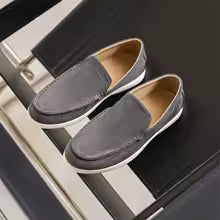 Gray loafers on a black surface with a white background