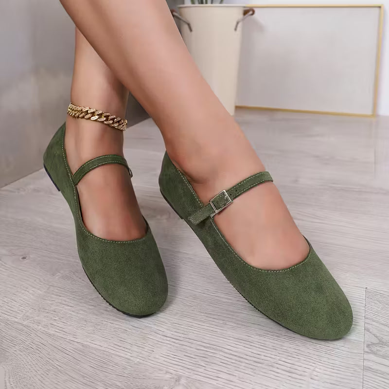 Green shoes worn by a person on a light wooden floor.