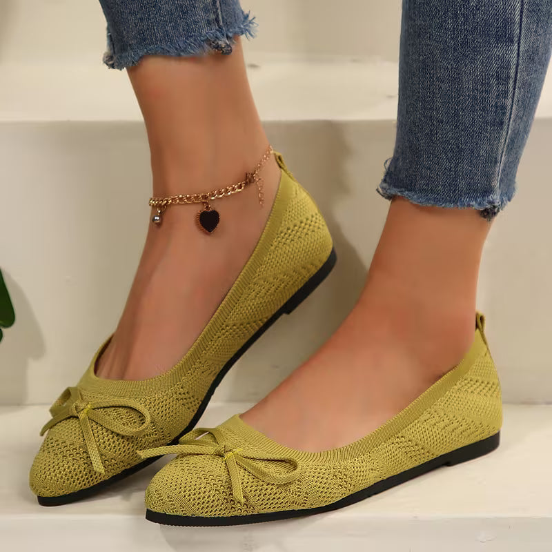 Green knitted flats with a bow on a neutral background