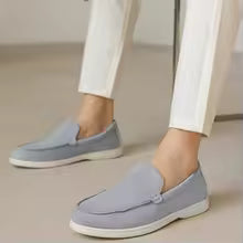 Light blue loafers worn with white pants on a neutral background