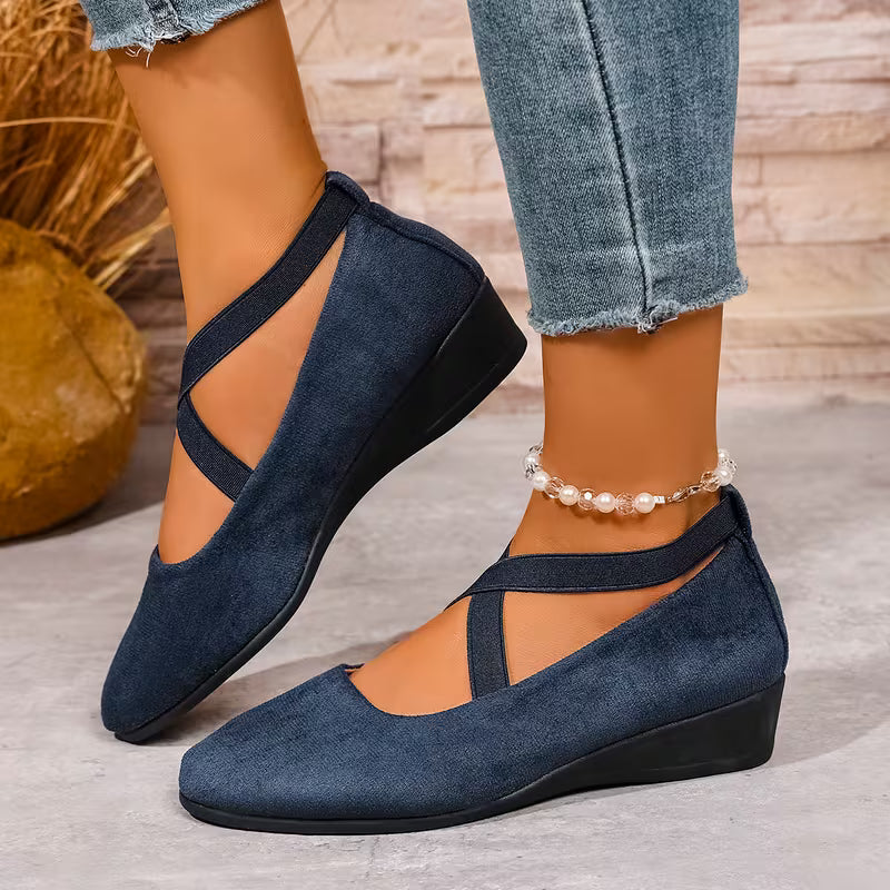 Blue wedge shoes worn with jeans on a neutral background