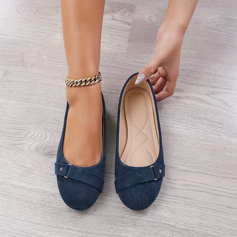 Blue suede shoes with a buckle on a wooden floor