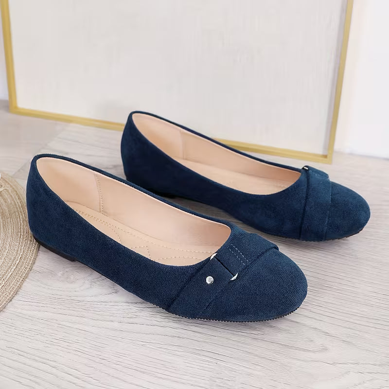 Pair of navy blue suede shoes on a light wooden floor.
