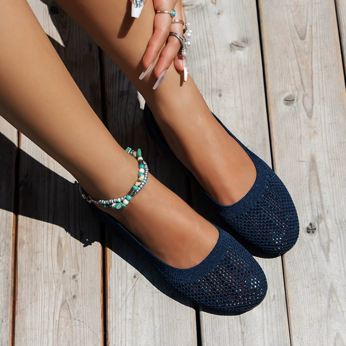 Navy blue flats worn on a wooden floor with a focus on the shoes.