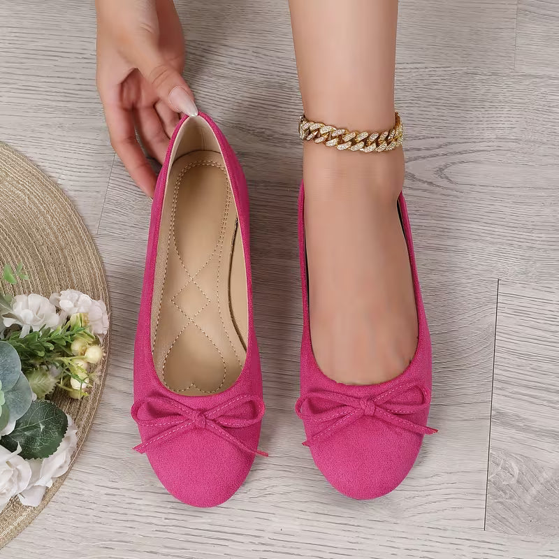 Pink shoes with bows on a wooden surface