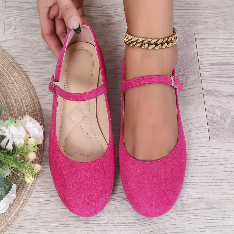 Pink shoes being worn on a light wooden floor with a small plant and decorative item.