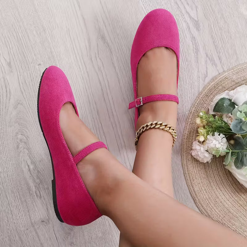 Pink flat shoes worn on a light wooden floor with a small plant in the background