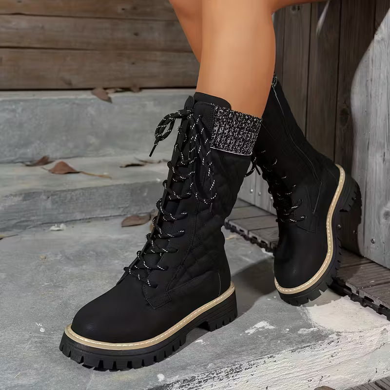 Black lace-up boots worn by a person on stone steps.