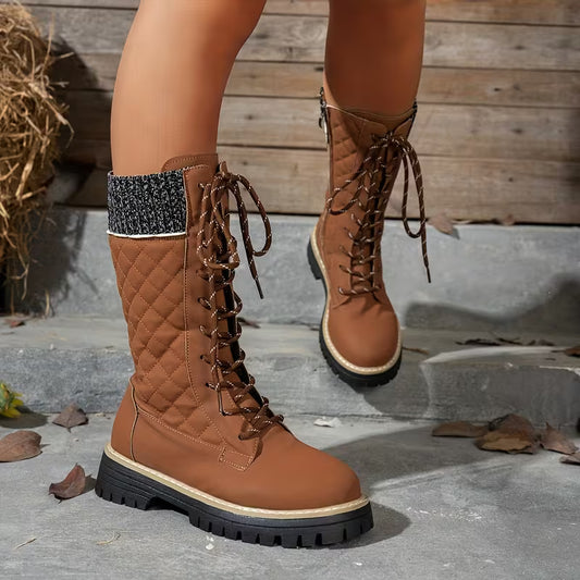 Brown quilted boots worn by a person on a wooden and stone surface.