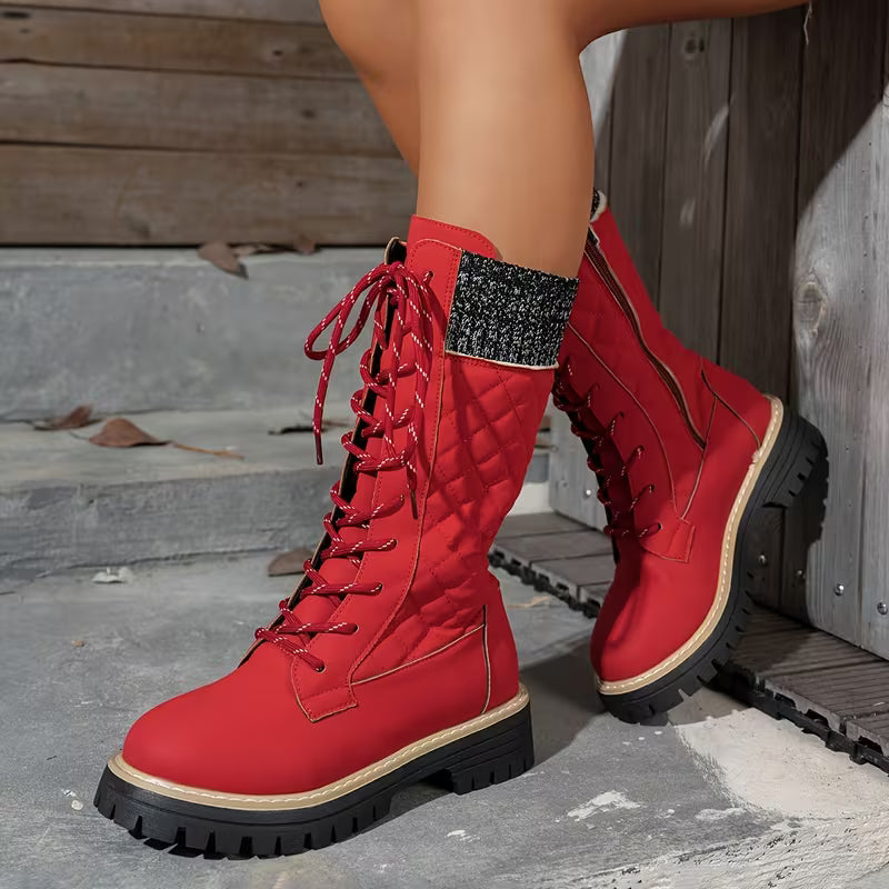 Red combat boots with black soles on a stone surface.