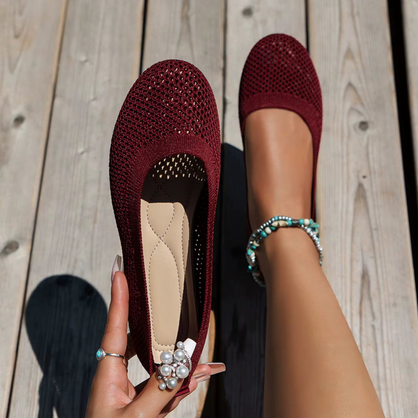 Maroon flats with embellishments on a wooden floor