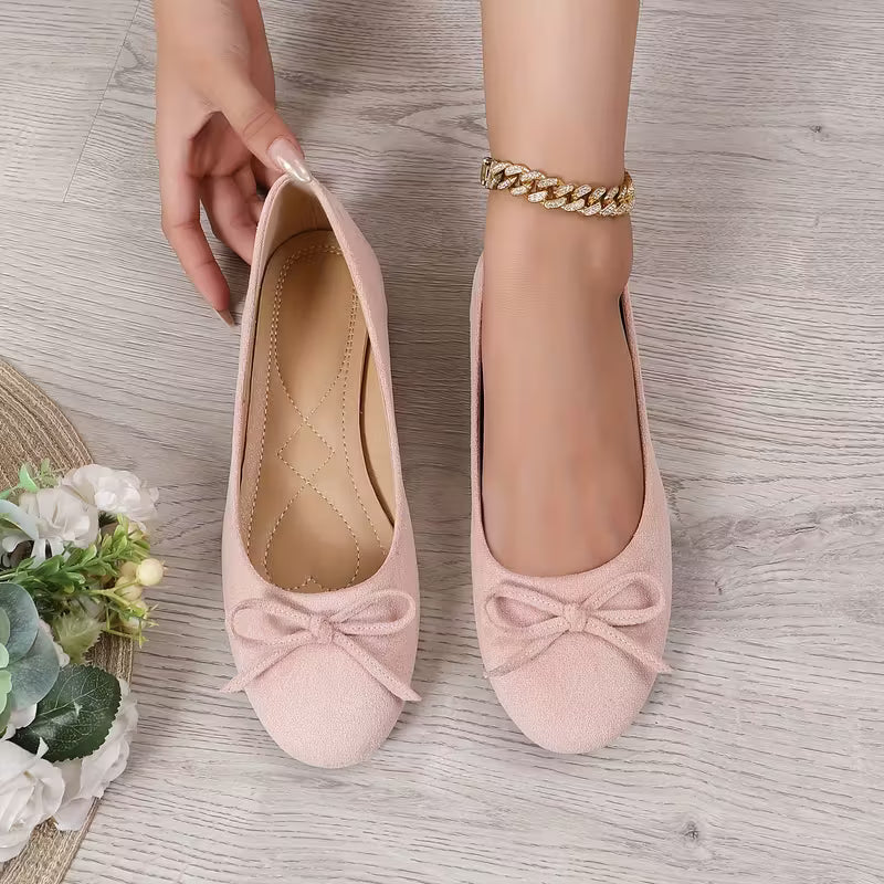 Pink shoes with bow details on a wooden floor