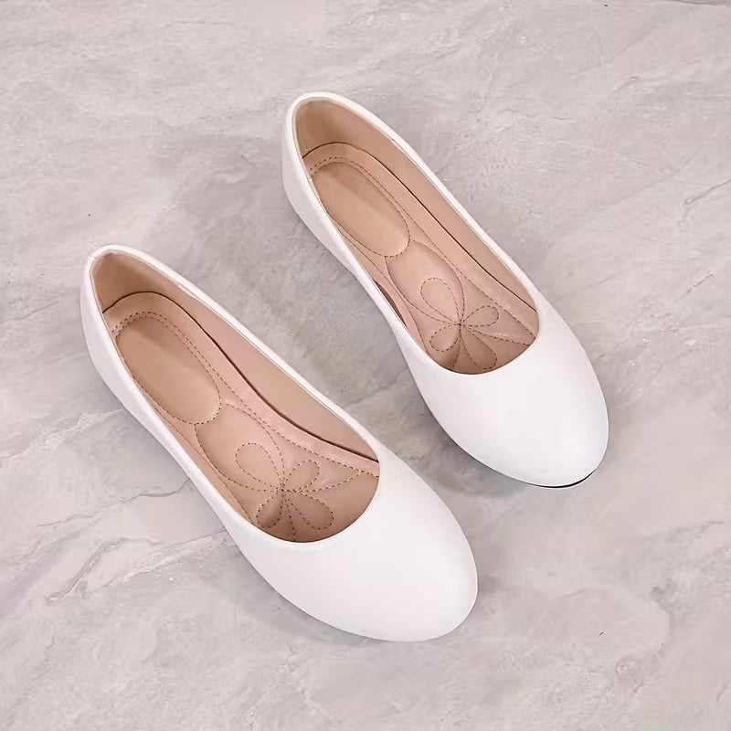 Pair of white flat shoes on a light gray surface