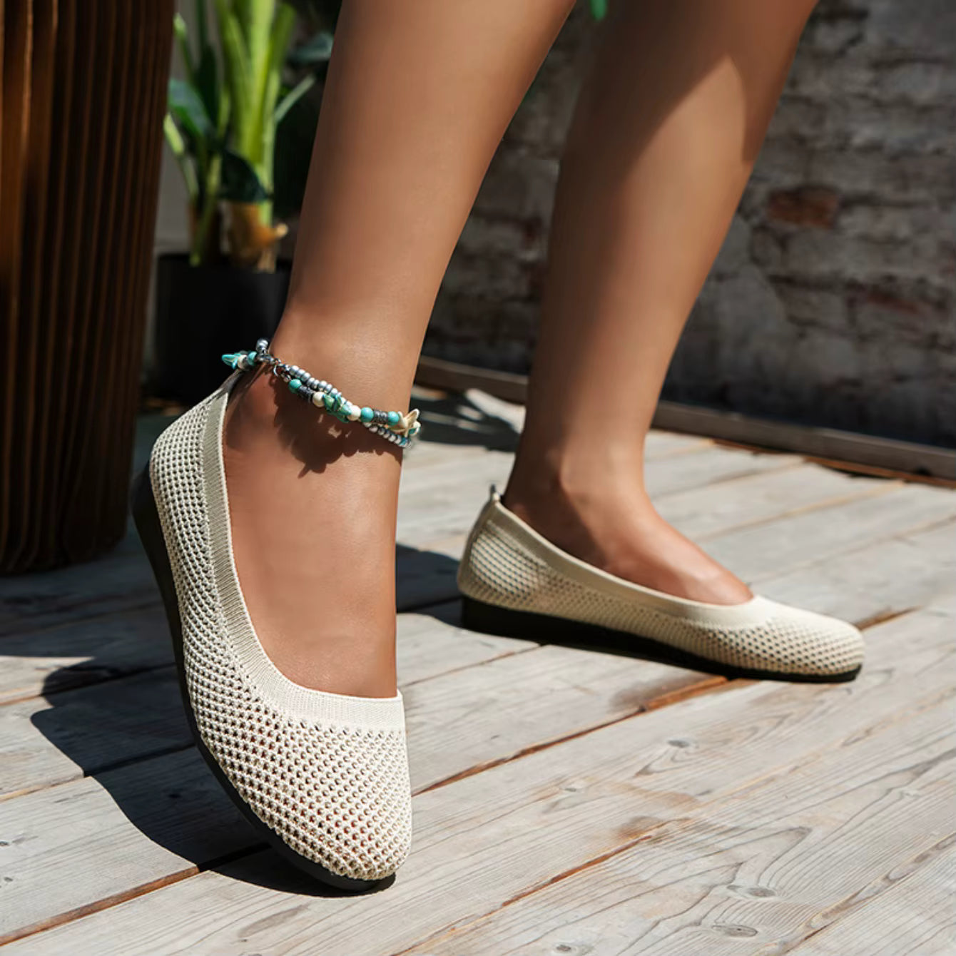Beige woven shoes worn on a wooden floor with a blurred background